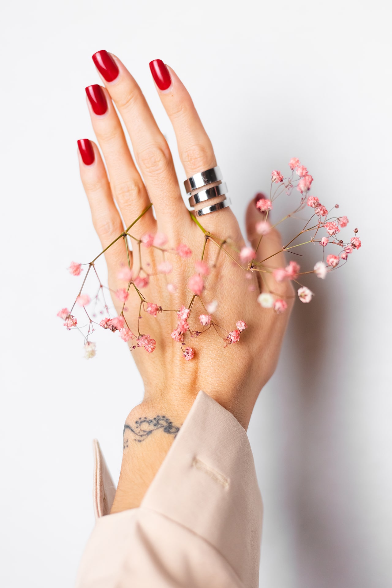 soft-gentle-photo-woman-hand-with-big-ring-red-manicure-hold-cute-little-pink-dried-flowers-white